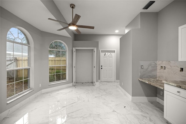 interior space with marble finish floor, a ceiling fan, visible vents, and baseboards