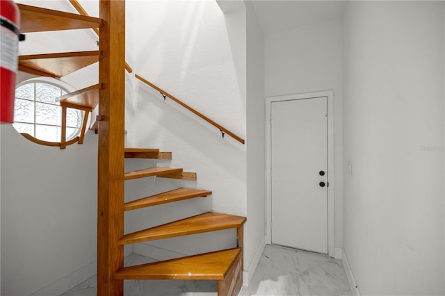 staircase with marble finish floor and baseboards