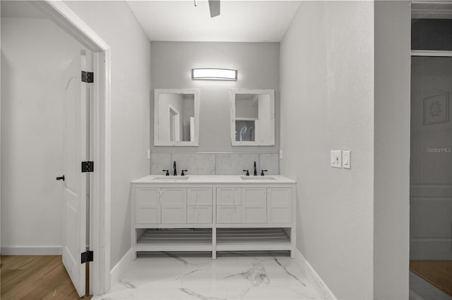 bathroom with a sink, baseboards, and double vanity