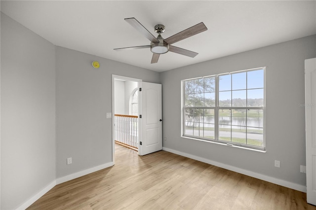 unfurnished room featuring baseboards, light wood-type flooring, and a water view