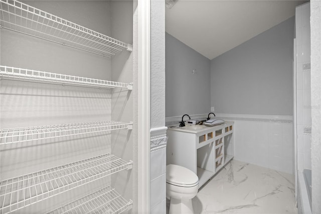 full bath featuring marble finish floor, a wainscoted wall, and toilet