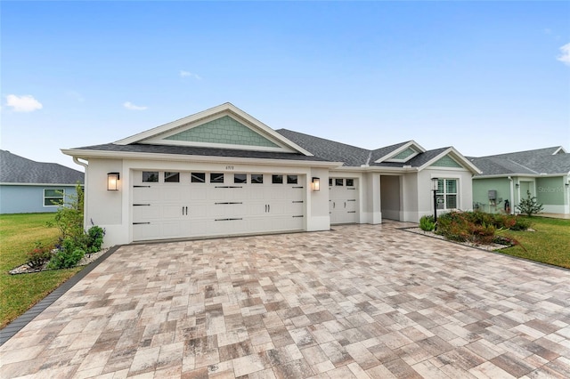 view of front of house featuring a front yard, decorative driveway, an attached garage, and stucco siding