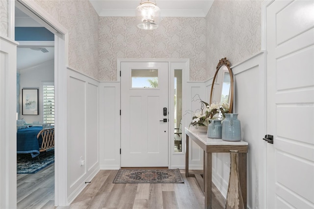 entrance foyer featuring wallpapered walls, wood finished floors, and wainscoting