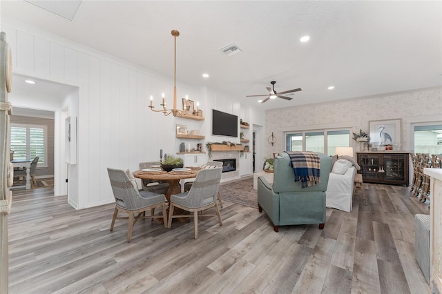 living room with light wood finished floors, visible vents, a glass covered fireplace, ceiling fan, and recessed lighting