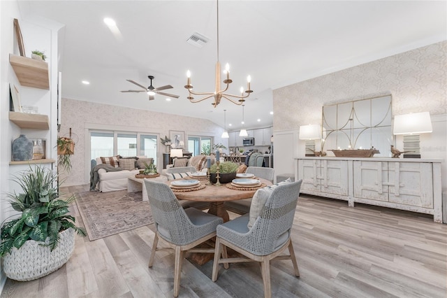 dining space with ceiling fan with notable chandelier, visible vents, wallpapered walls, light wood finished floors, and crown molding