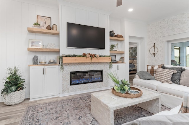 living room featuring recessed lighting, light wood-style flooring, and a tiled fireplace