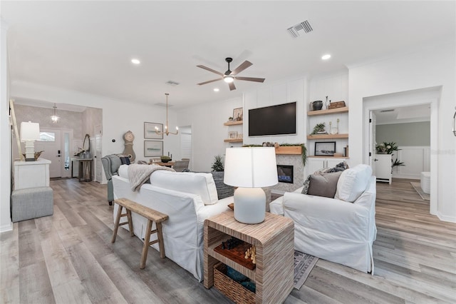 living area with light wood-style floors, a glass covered fireplace, visible vents, and recessed lighting