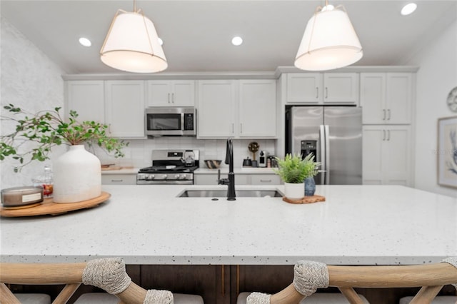 kitchen with stainless steel appliances, a sink, hanging light fixtures, and a breakfast bar area