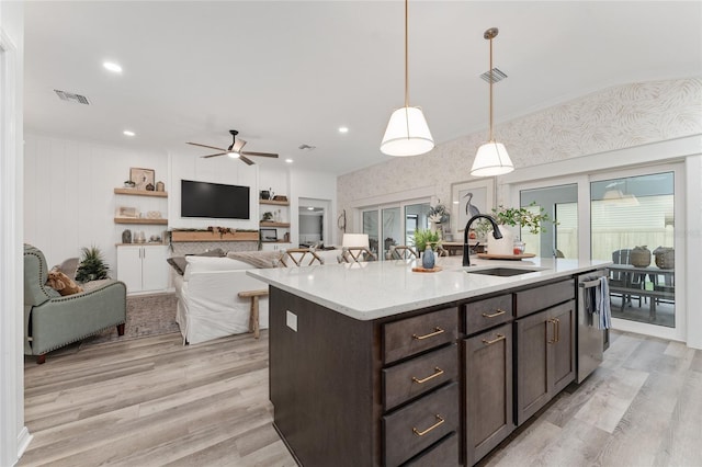 kitchen featuring stainless steel dishwasher, a sink, light wood finished floors, and dark brown cabinetry