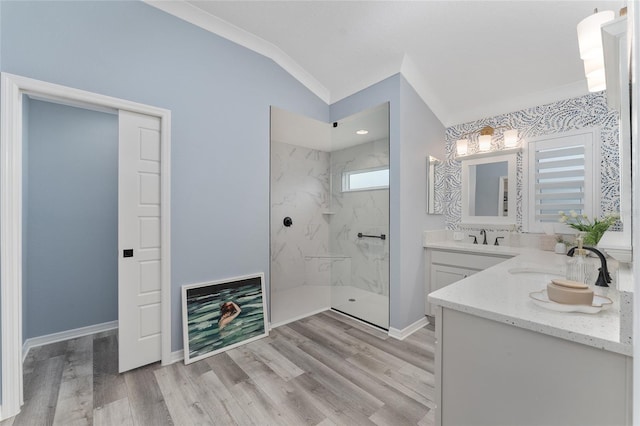 bathroom featuring a marble finish shower, baseboards, lofted ceiling, wood finished floors, and a sink