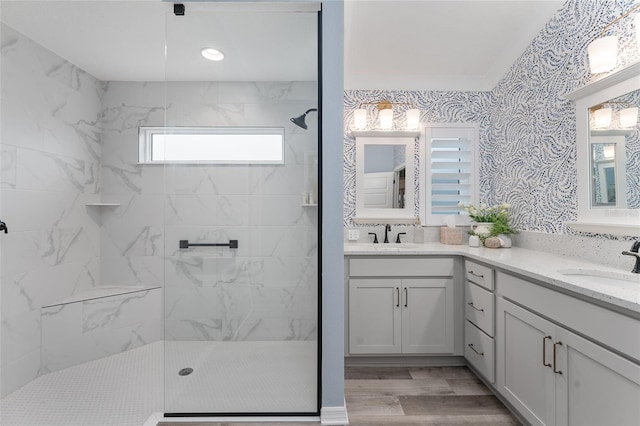 bathroom with double vanity, wood finished floors, walk in shower, and a sink