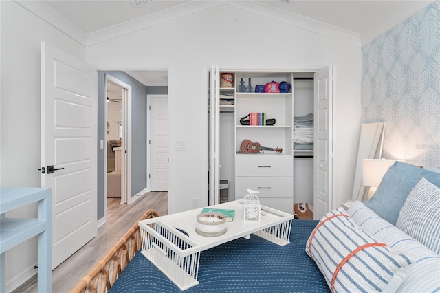 interior space with crown molding, a closet, vaulted ceiling, and wood finished floors