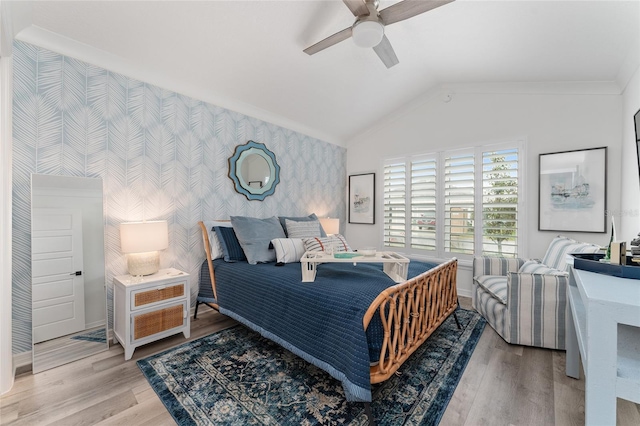 bedroom featuring wallpapered walls, baseboards, lofted ceiling, an accent wall, and wood finished floors