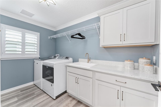 laundry room featuring a sink, visible vents, light wood-style floors, cabinet space, and washing machine and clothes dryer