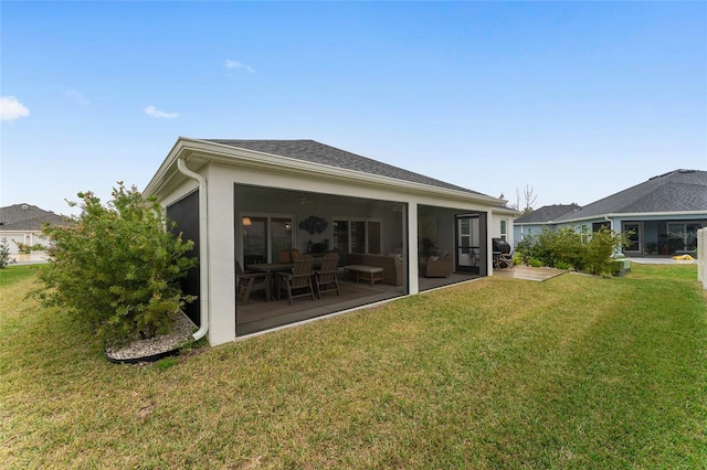 rear view of property with roof with shingles, a yard, a patio, stucco siding, and a sunroom