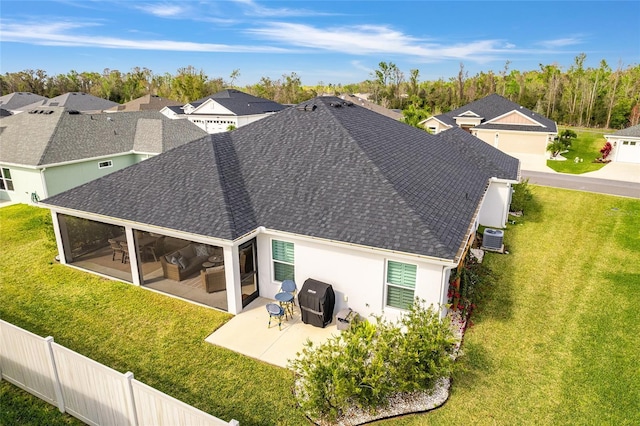 back of house featuring a lawn, a patio, a sunroom, roof with shingles, and cooling unit