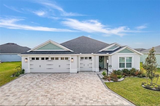 ranch-style house featuring an attached garage, roof with shingles, decorative driveway, stucco siding, and a front yard