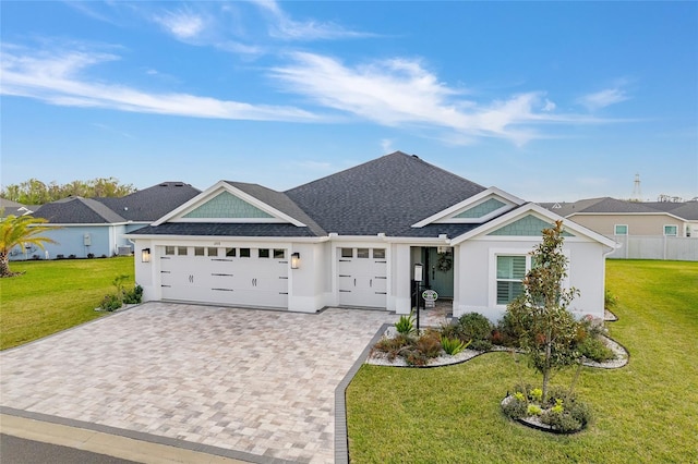 view of front of property with an attached garage, roof with shingles, decorative driveway, and a front yard