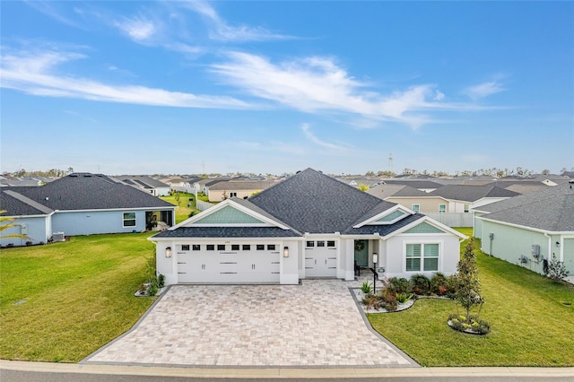 ranch-style house featuring a garage, a residential view, decorative driveway, and a front yard