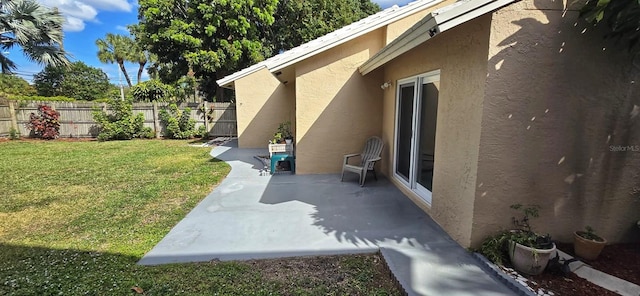 view of side of property with stucco siding, fence, and a yard