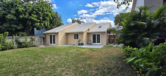 rear view of property with stucco siding, a fenced backyard, a lawn, and a patio