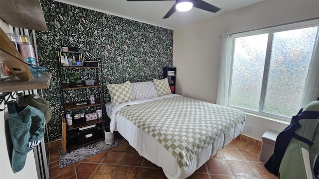 bedroom with dark tile patterned floors, multiple windows, and a ceiling fan