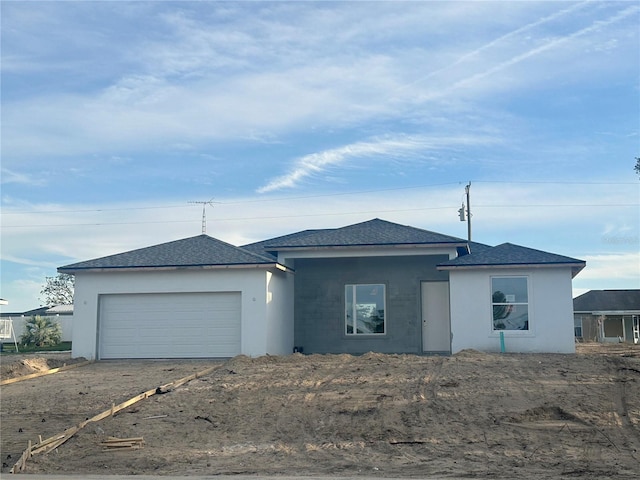 view of front of house with a shingled roof, an attached garage, and stucco siding