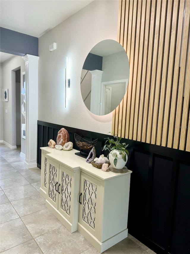 bathroom with a wainscoted wall, decorative columns, and tile patterned flooring