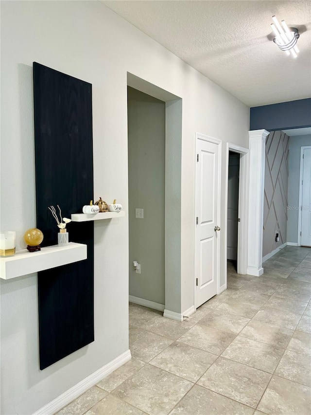 interior space with a textured ceiling and baseboards