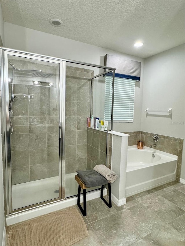 full bath featuring a shower stall, a textured ceiling, and a bath