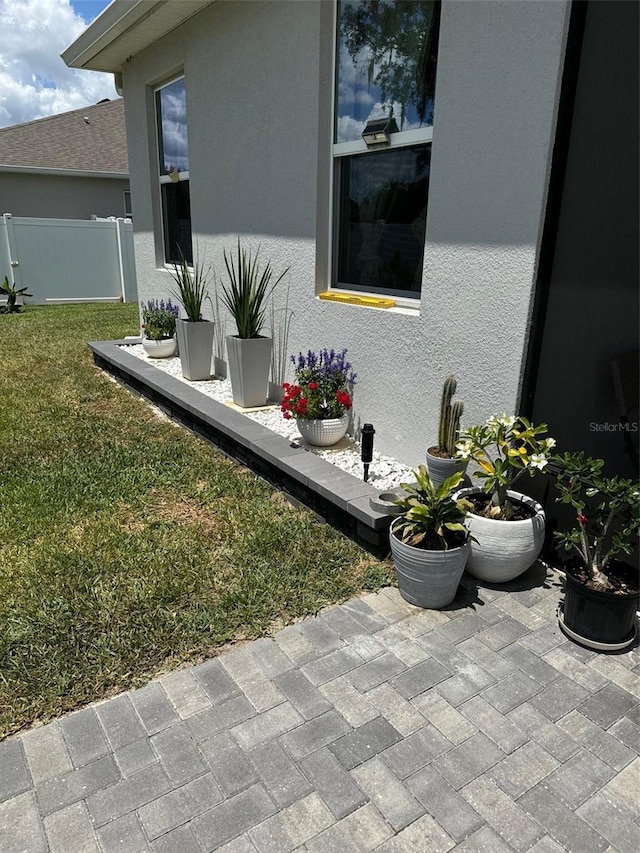 exterior space featuring a patio area, fence, a lawn, and stucco siding