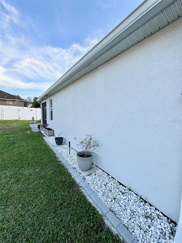 view of home's exterior featuring a lawn, fence, and stucco siding