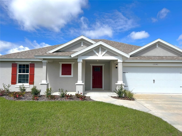 view of front of property with stucco siding, a shingled roof, concrete driveway, a front yard, and a garage