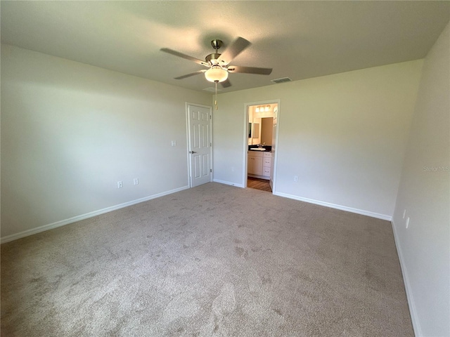 unfurnished bedroom with carpet, visible vents, a ceiling fan, ensuite bath, and baseboards