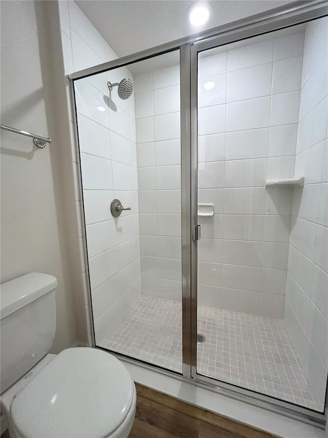 full bath featuring a stall shower, toilet, and wood finished floors