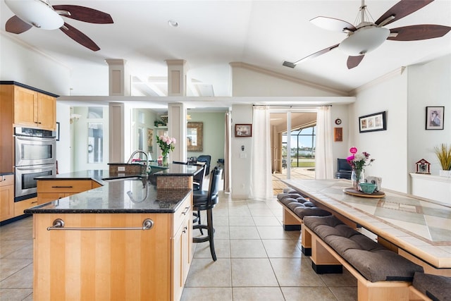 kitchen with vaulted ceiling, crown molding, a sink, double oven, and ceiling fan