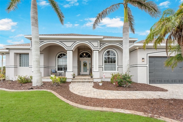 mediterranean / spanish house with a front lawn, driveway, a porch, a garage, and stucco siding