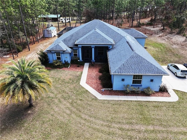 view of front of house featuring a shingled roof, a front lawn, and stucco siding