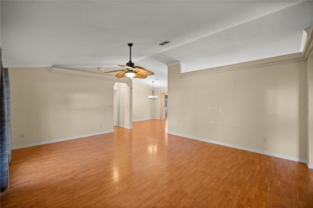 unfurnished room featuring lofted ceiling, visible vents, wood finished floors, and ceiling fan with notable chandelier