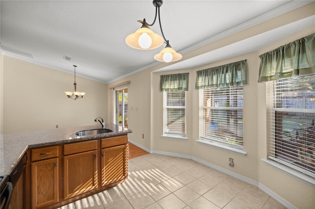 kitchen featuring visible vents, brown cabinets, hanging light fixtures, crown molding, and a sink