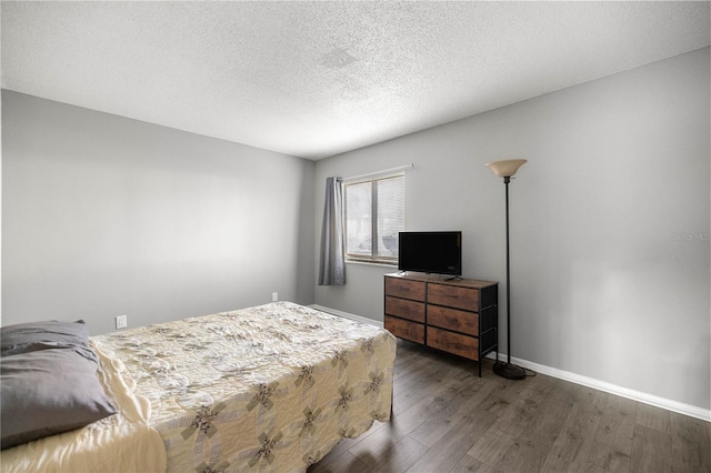 bedroom featuring a textured ceiling, wood finished floors, and baseboards