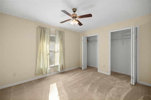 unfurnished bedroom with baseboards, ceiling fan, carpet flooring, and multiple closets