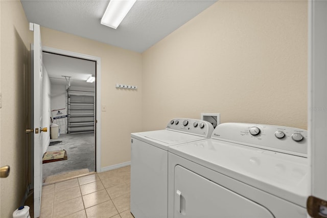 laundry area featuring light tile patterned floors, washing machine and dryer, a textured ceiling, laundry area, and baseboards