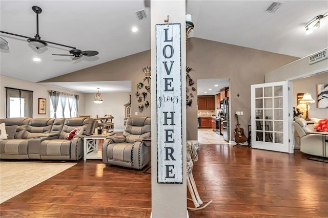 living area featuring dark wood-type flooring, lofted ceiling, and visible vents