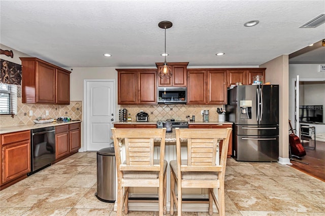 kitchen with stainless steel appliances, visible vents, light countertops, backsplash, and pendant lighting