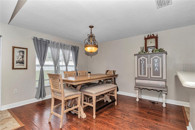 dining space featuring visible vents, dark wood finished floors, a textured ceiling, and baseboards