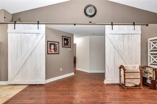 sitting room featuring vaulted ceiling, dark wood finished floors, baseboards, and a barn door