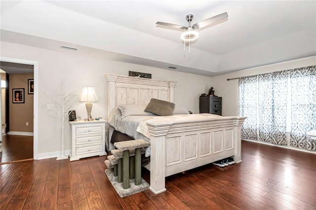 bedroom featuring baseboards, visible vents, dark wood finished floors, ceiling fan, and a tray ceiling