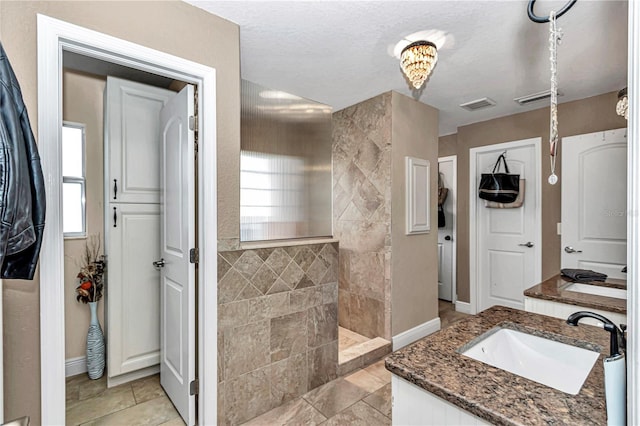 bathroom with visible vents, vanity, baseboards, and a walk in shower