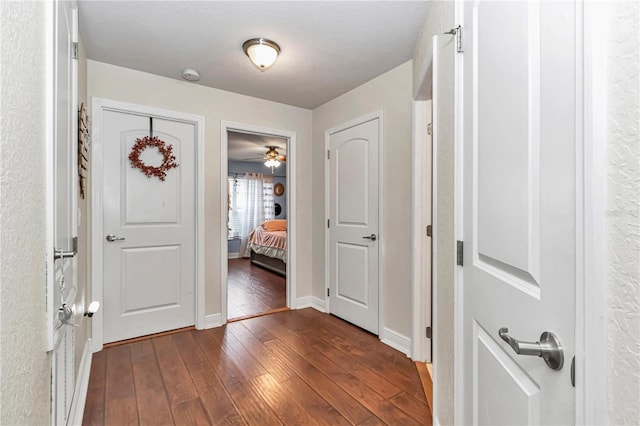 corridor with dark wood-style floors and baseboards